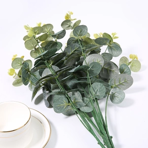 Detail of silk eucalyptus leaves in a vase next to a white coffee cup for home decor