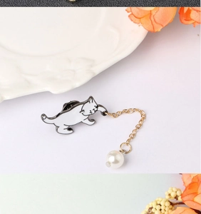 Detail of white enamel cat brooch with gold chain and elegant pearl pendant accessory