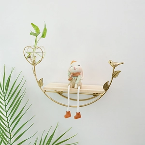 Golden wall shelf with wooden plate featuring heart-shaped glass vase and metal bird