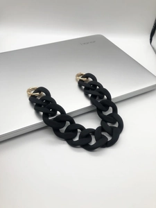 Close-up of black acrylic handbag chain strap with gold metal lobster clasps