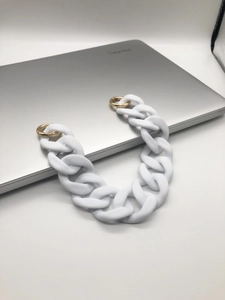 Detail of white matte acrylic chain strap with gold round spring buckles on a laptop