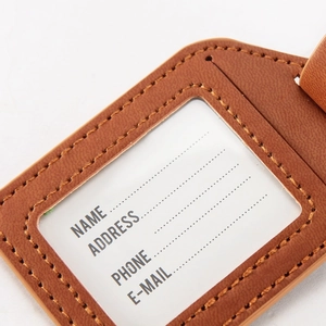 Macro view of brown PU leather luggage tag with transparent ID window and card slot