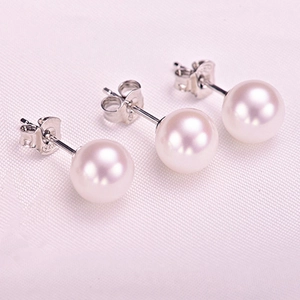 Close-up of three white round pearl earrings with 925 sterling silver hallmarks