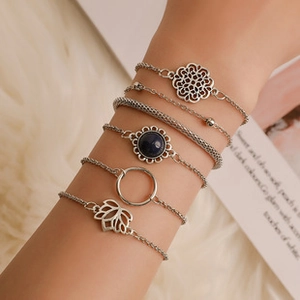 Macro detail of bohemian silver chain bracelets featuring a navy blue gemstone charm