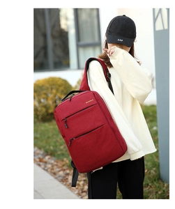 Detailed view of red waterproof oxford backpack worn by model in an outdoor setting