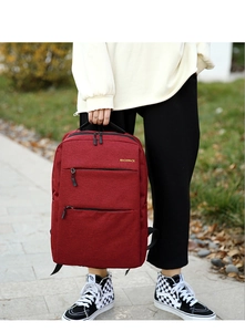 Detail of a red waterproof Oxford backpack featuring gold lettering and front zipper pockets