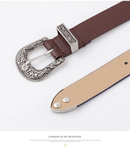 Gros plan sur ceinture en cuir marron avec boucle et passant en argent vieilli gravé