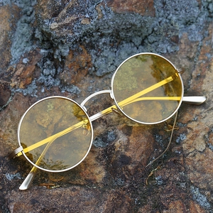 Vintage round polarized sunglasses with yellow lenses and golden metal frame on rock surface
