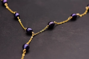Macro shot of elegant deep purple freshwater pearls on a delicate gold Y-shaped necklace