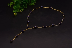 Macro view of Y-shaped necklace featuring natural black pearls and gold-plated chain