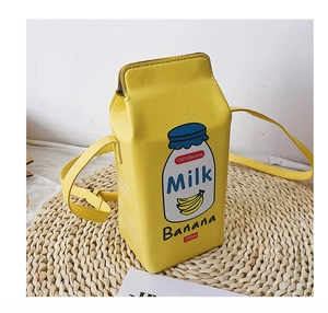Top view of creative yellow banana milk carton crossbody bag on a woven straw mat