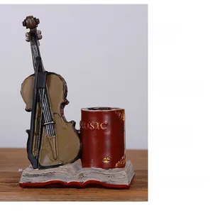 Close-up of vintage resin violin and book shaped desk organizer and creative pen holder