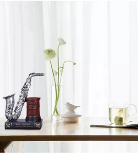 Detail view of retro resin saxophone and red postbox pen holder on a wooden desk surface