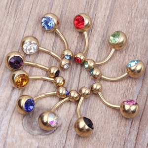 Set of 10 gold-plated navel rings with colorful crystals on a light wood background