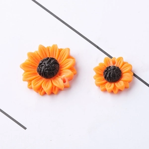 Orange daisy resin flower charms for DIY jewelry making in two sizes on white surface