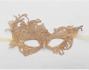 Close-up of golden lace masquerade mask with intricate embroidery and silk ribbons