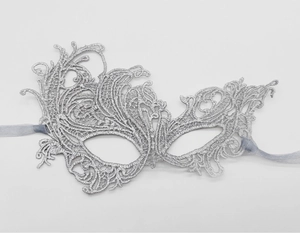 Macro shot of silver lace embroidery detail on elegant masquerade party mask