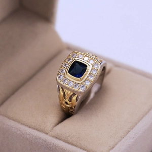 Detailed view of square blue gemstone ring with two-tone silver and gold engraved band