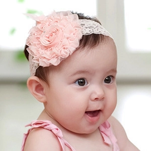 Gros plan d'un bandeau en dentelle rose pour bébé avec grande fleur en tulle souple