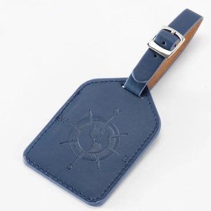 Close-up of a navy PU leather luggage tag with embossed compass and globe patterns