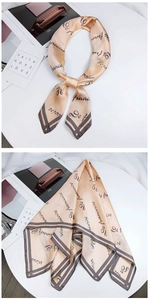 Detail of champagne gold silk scarf featuring elegant black cursive letter printing and edges