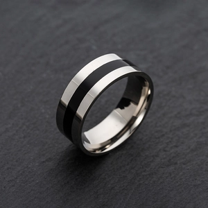 Minimalist silver stainless steel men's ring with black stripe on dark rock background