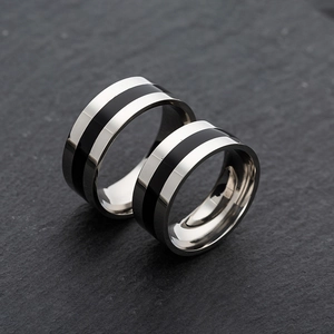 Macro detail of silver and black enamel striped stainless steel rings for men on stone