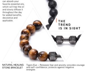 Macro detail of lava rock and tiger eye stone beads with engraved dumbbell charm