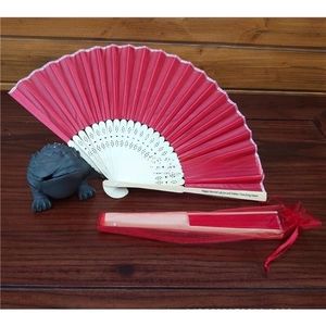 Detail of red silk folding fan with wooden ribs and matching drawstring mesh organza bag