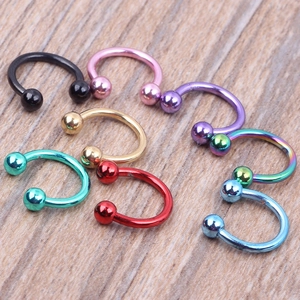 Detail view of colorful horseshoe piercing rings in eight metallic finishes on wood