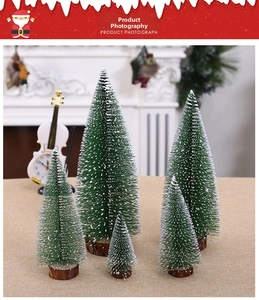 Miniature snow-flocked Christmas pine trees with wooden bases in a cozy home setting