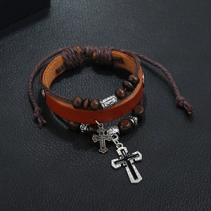 Macro shot of multilayer leather bracelet with wooden beads and silver cross charms