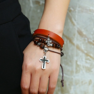 Close-up of multilayer leather bracelet set with wooden beads and silver cross pendants