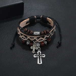 Macro shot of multi-layer leather bracelet featuring wooden beads and metal cross charms