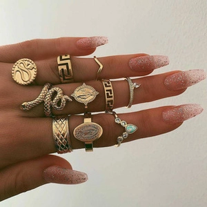 Detail van goudkleurige legering ringen met slang, muntreliëf en geometrische patronen