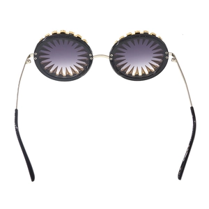 Detail view of round sunglasses with golden spikes and purple gradient lenses