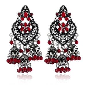 Close-up of antique silver Jhumka earrings with red gemstones and bead tassels