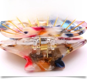 Close-up of shell-shaped cellulose acetate hair claw clip with colorful marble texture