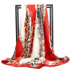 Close-up of chain and leopard print satin square scarf hanging on a display stand