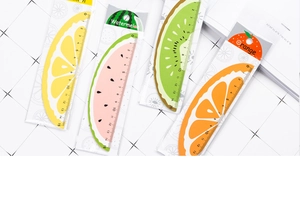 Flat lay of four colorful 15cm fruit-shaped wooden rulers with cute cartoon patterns