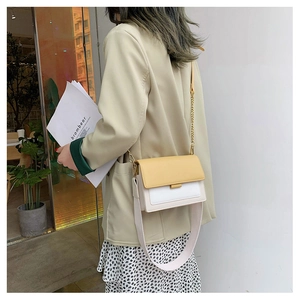 Detail view of contrast color crossbody bag with yellow flap and metal chain strap