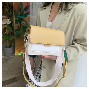 Detail of color-block crossbody bag with yellow flap, cream body, and metal chain strap