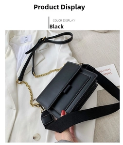 Detail of black crossbody bag with white contrast stitching and gold chain on white blazer