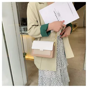 Detail of color-block crossbody bag with gold chain strap on beige suit model