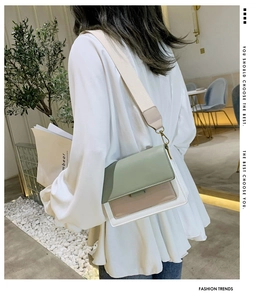 Detail of color-block crossbody bag in green and pink leather on model with gold hardware