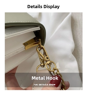 Close-up of the golden metal hook hardware on the light green and white handbag