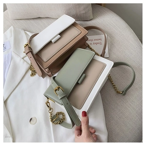 Detail of color-block crossbody bag with gold chain strap on white blazer background