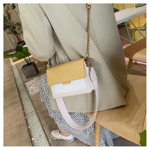 Detail of color-block flap bag featuring a yellow top, cream body, and chic gold chain strap