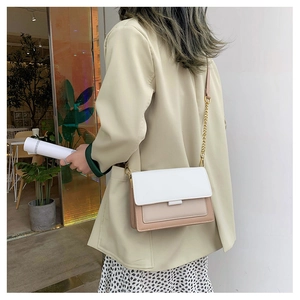 Detail shot of a minimalist contrast color crossbody bag with gold chain strap on shoulder