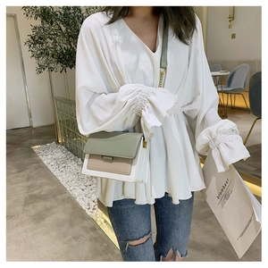 Detail of color-block flap bag with metal chain strap and white V-neck chiffon shirt